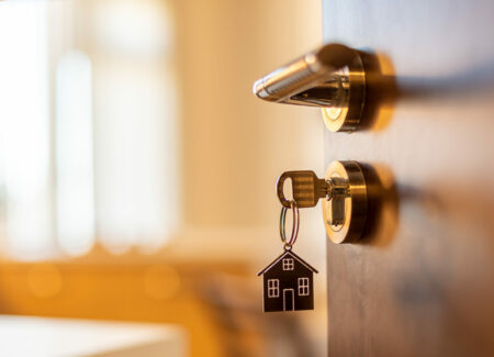 Buying waterfront property. Open door to a new home. Door handle with key and home shaped keychain. Mortgage, investment, real estate, property and new home concept